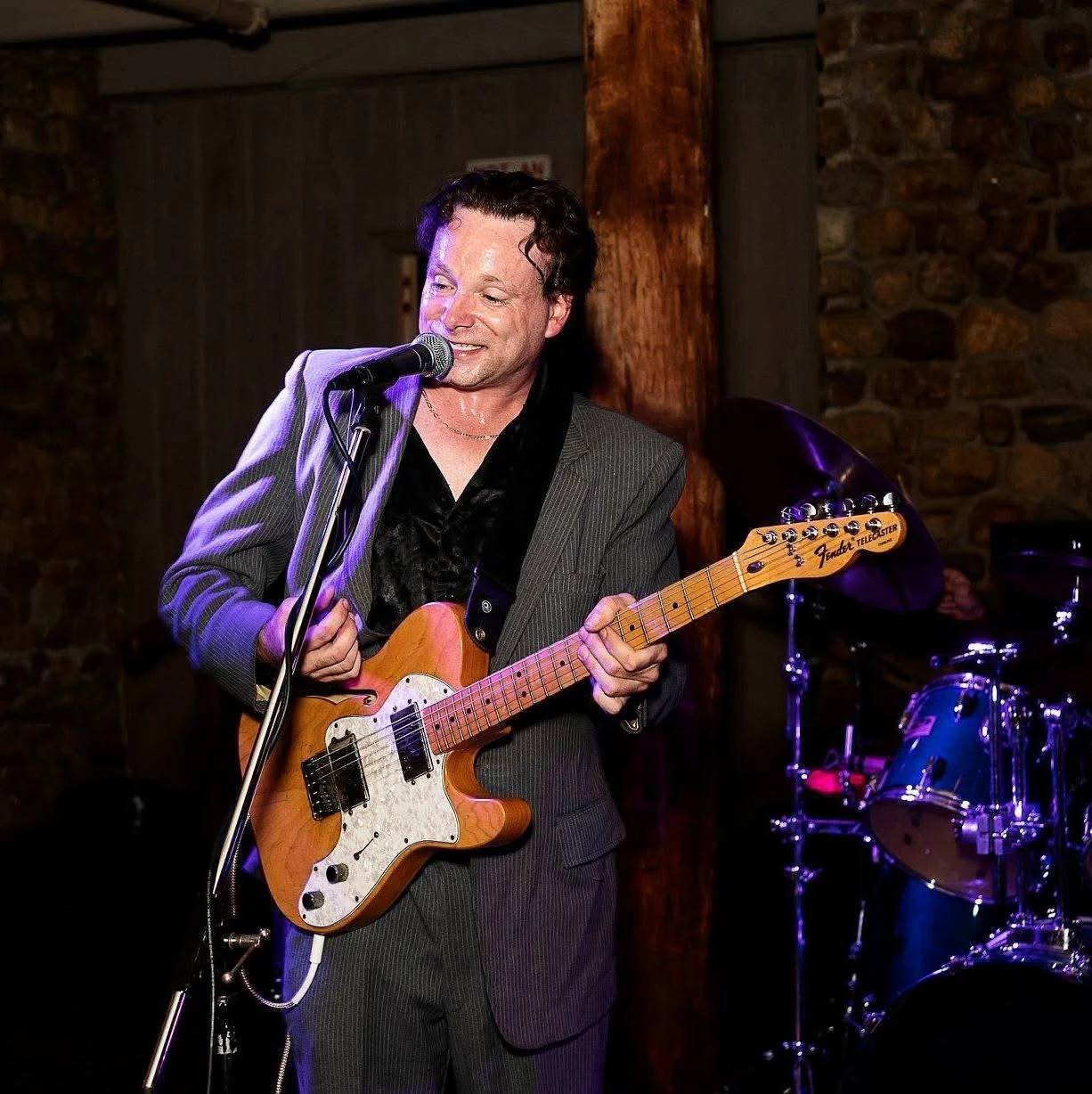 Chris Zemba singing at a stone-walled reception