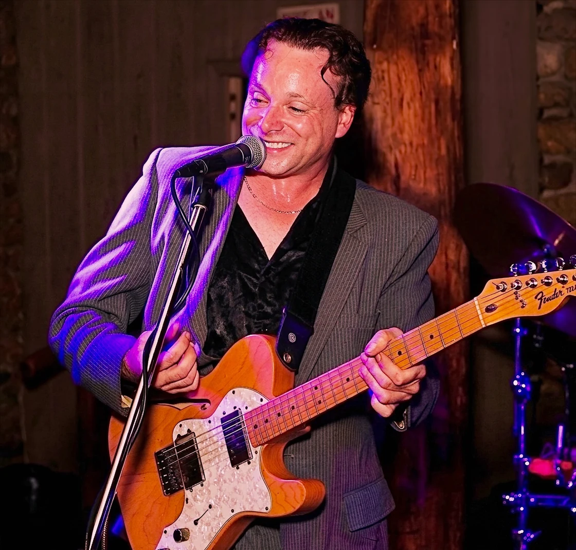 Chris Zemba smiling mid-song at a wedding reception